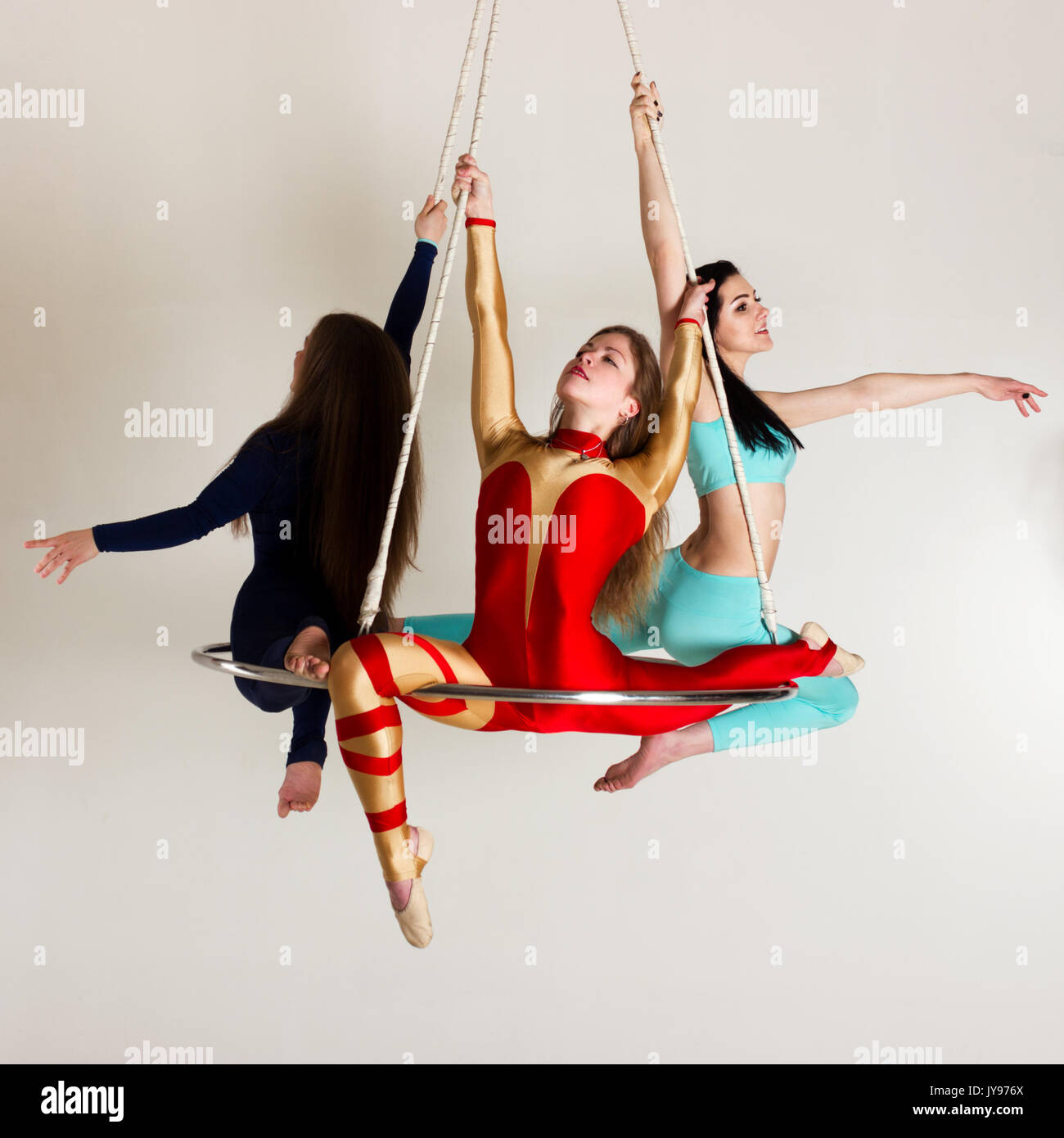 Young woman`s trio doing som acrobatic tricks on aerial luster Stock Photo